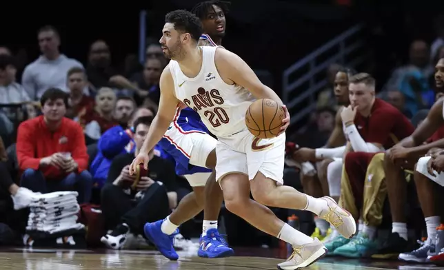 Cleveland Cavaliers forward Georges Niang (20) drives against Philadelphia 76ers guard Tyrese Maxey during the first half of an NBA basketball game Friday, March 29, 2024, in Cleveland. (AP Photo/Ron Schwane)