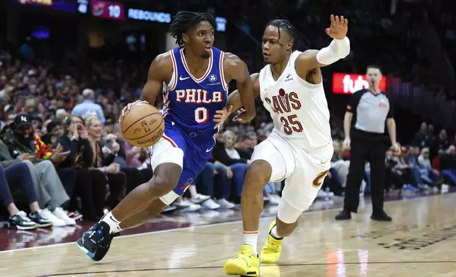 Philadelphia 76ers guard Tyrese Maxey (0) drives against Cleveland Cavaliers forward Isaac Okoro (35) during the first half of an NBA basketball game Friday, March 29, 2024, in Cleveland. (AP Photo/Ron Schwane)