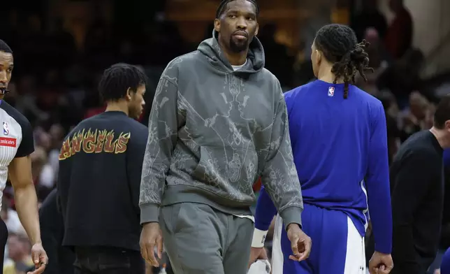 Injured Philadelphia 76ers center Joel Embiid stands during a timeout in the second half of the team's NBA basketball game against the Cleveland Cavaliers, Friday, March 29, 2024, in Cleveland. (AP Photo/Ron Schwane)