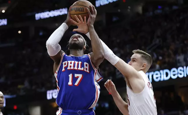 Philadelphia 76ers guard Buddy Hield (17) shoots against Cleveland Cavaliers guard Sam Merrill during the first half of an NBA basketball game Friday, March 29, 2024, in Cleveland. (AP Photo/Ron Schwane)