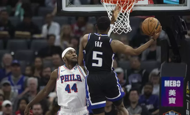 Sacramento Kings guard De'Aaron Fox (5) scores a basket past Philadelphia 76ers forward Paul Reed (44) in the first half of an NBA basketball game in Sacramento, Calif., Monday, March 25, 2024. (AP Photo/José Luis Villegas)