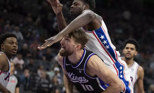 Philadelphia 76ers center Mo Bamba, top, fouls Sacramento Kings forward Domantas Sabonis (10) as he attempts a shot in the second half of an NBA basketball game in Sacramento, Calif., Monday, March 25, 2024. The Kings won 108-96. (AP Photo/José Luis Villegas)