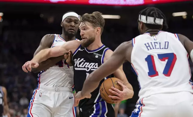 Sacramento Kings forward Domantas Sabonis (10) drives to the basket as Philadelphia 76ers forward Paul Reed (44) and guard Buddy Hield (17) defend in the second half of an NBA basketball game in Sacramento, Calif., Monday, March 25, 2024. The Kings won 108-96. (AP Photo/José Luis Villegas)