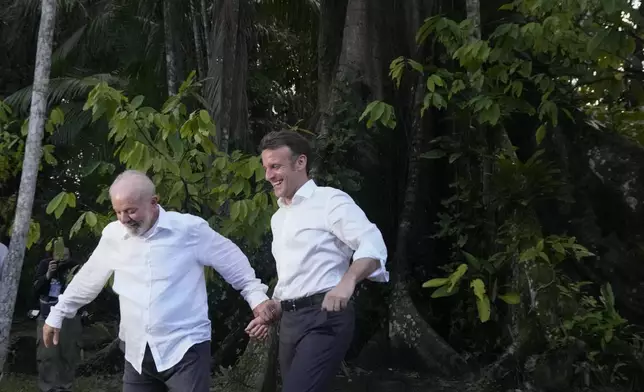 Brazil's President Luiz Inacio Lula da Silva, left, and French President Emmanuel Macron arrive on Combu Island, near Belem, Para state, Brazil, Tuesday, March 26, 2024. (AP Photo/Eraldo Peres).