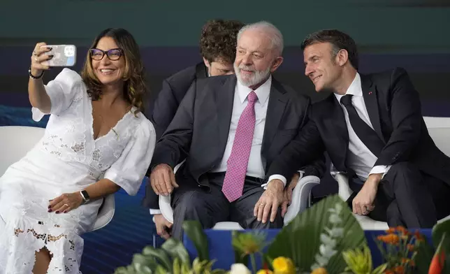 Brazilian first lady Rosangela da Silva takes a selfie with France's President Emmanuel Macron, right, and her husband Brazilian President Luiz Inacio Lula da Silva during the launch ceremony of the Tonelero submarine, made in Brazil with French technology, in Itaguai, Rio de Janeiro state, Brazil, Wednesday, March 27, 2024. Macron is on a three-day visit to Brazil. (AP Photo/Silvia Izquierdo)