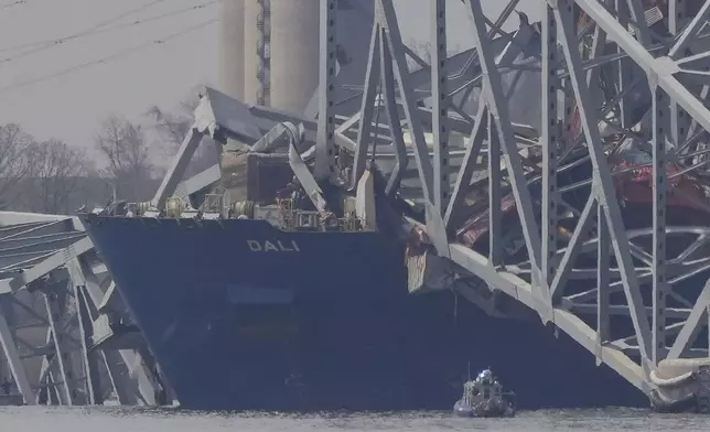A container rests against wreckage of the Francis Scott Key Bridge on Tuesday, March 26, 2024, as seen from Sparrows Point, Md. The ship rammed into the major bridge in Baltimore early Tuesday, causing it to collapse in a matter of seconds and creating a terrifying scene as several vehicles plunged into the chilly river below. (AP Photo/Matt Rourke)