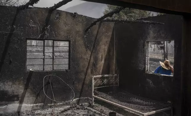 A resident looks at his home destroyed by wildfires in Maltrata, Mexico, Monday, March 25, 2024. Emergency crews are working to contain wildfires burning across parts of the high mountains in west-central Veracruz state. (AP Photo/Felix Marquez)