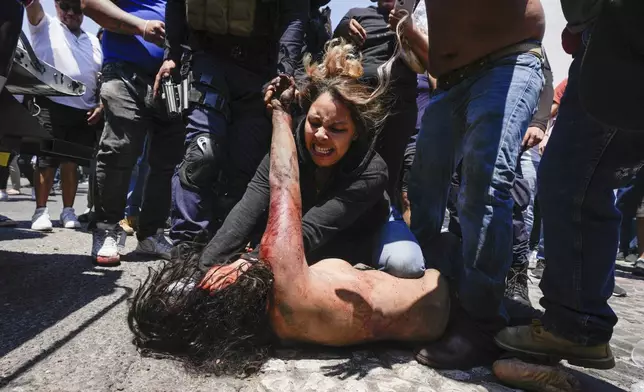 A mob beats a woman they suspect of kidnapping and killing an 8-year-old girl, after dragging her out of a police vehicle, in Taxco, Mexico, Thursday, March 28, 2024. (AP Photo/Fernando Llano)