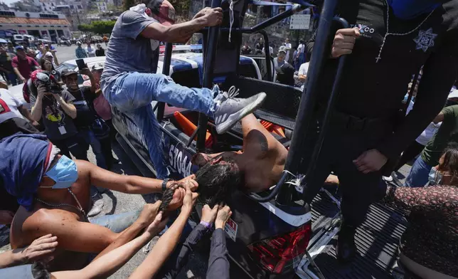 A woman suspected in the kidnapping and killing of an 8-year-old girl, is dragged out of a police vehicle by a mob in Taxco, Mexico, Thursday, March 28, 2024. (AP Photo/Fernando Llano)