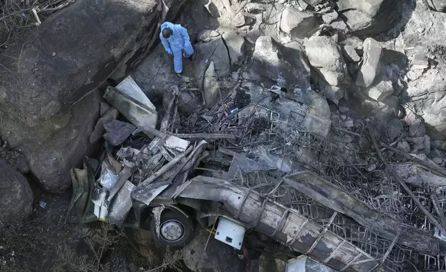 The wreckage of a bus lays in a ravine a day after it plunged off a bridge on the Mmamatlakala mountain pass between Mokopane and Marken, around 300km (190 miles) north of Johannesburg, South Africa, Friday, March 29, 2024. The bus carrying worshippers on a long-distance trip from Botswana to an Easter weekend church gathering in South Africa plunged off a bridge on a mountain pass Thursday and burst into flames as it hit the rocky ground below, killing at least 45 people, authorities said. The only survivor was an 8-year-old child who was receiving medical attention for serious injuries. (AP Photo/Themba Hadebe)