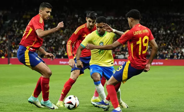 Brazil's Rodrygo, centre right, tries to get past Spain's Rodrigo, left, Alvaro Morata, 2nd left and Lamine Yamal during a friendly soccer match between Spain and Brazil at the Santiago Bernabeu stadium in Madrid, Spain, Tuesday, March 26, 2024. (AP Photo/Jose Breton)