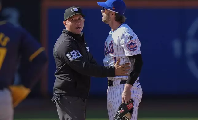 Second base umpire Jonathan Parra (121) restrains New York Mets' Jeff McNeil as benches cleared during the eighth inning of a baseball game against the Milwaukee Brewers Friday, March 29, 2024, in New York. (AP Photo/Frank Franklin II)