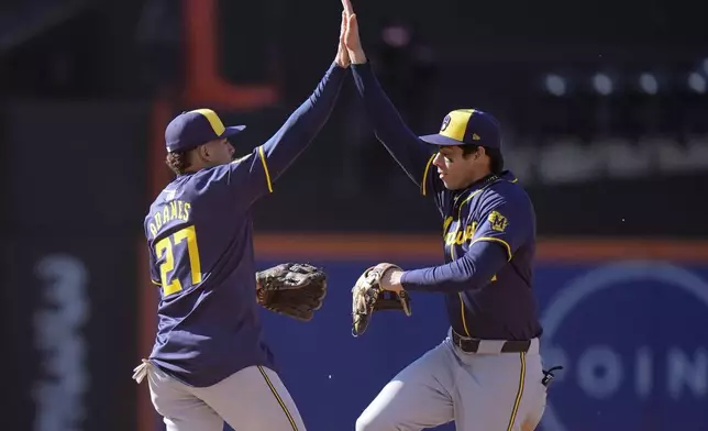 Milwaukee Brewers' Christian Yelich, right, celebrates with Willy Adames, left, after a baseball game against the New York Mets Friday, March 29, 2024, in New York. The Brewers won 3-1. (AP Photo/Frank Franklin II)