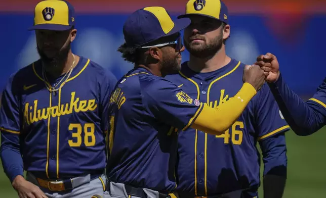 Milwaukee Brewers' Jackson Chourio (11) fist bumps teammates before a baseball game against the New York Mets Friday, March 29, 2024, in New York. (AP Photo/Frank Franklin II)