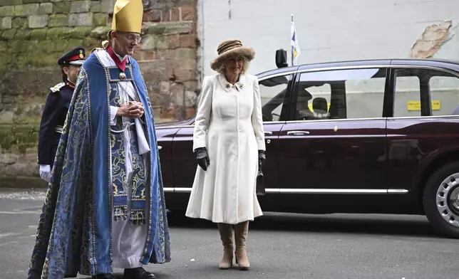 Britain's Queen Camilla is greeted by Bishop of Worcester Cathedral, The Right Reverend Dr John Inge, left, as she arrives for the Royal Maundy Service where she distributes the Maundy money to 75 men and 75 women, mirroring the age of the monarch, in Worcester Cathedral, Worcester, England, Thursday, March 28, 2024 to thank them for their outstanding Christian service and for making a difference to the lives of people in their local communities. Maundy Thursday is the Christian holy day falling on the Thursday before Easter. The monarch commemorates Maundy by offering 'alms' to senior citizens. Each recipient receives two purses, one red and one white. (Justin Tallis, Pool Photo via AP)