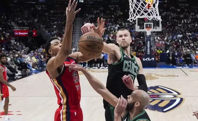 Boston Celtics center Kristaps Porzingis blocks a shot by New Orleans Pelicans guard Trey Murphy III (25) in the second half of an NBA basketball game in New Orleans, Saturday, March 30, 2024. The Celtics won 104-92. (AP Photo/Gerald Herbert)