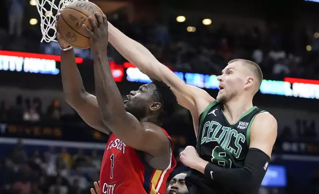 New Orleans Pelicans forward Zion Williamson (1) goes to the basket against Boston Celtics center Kristaps Porzingis (8) in the first half of an NBA basketball game in New Orleans, Saturday, March 30, 2024. (AP Photo/Gerald Herbert)