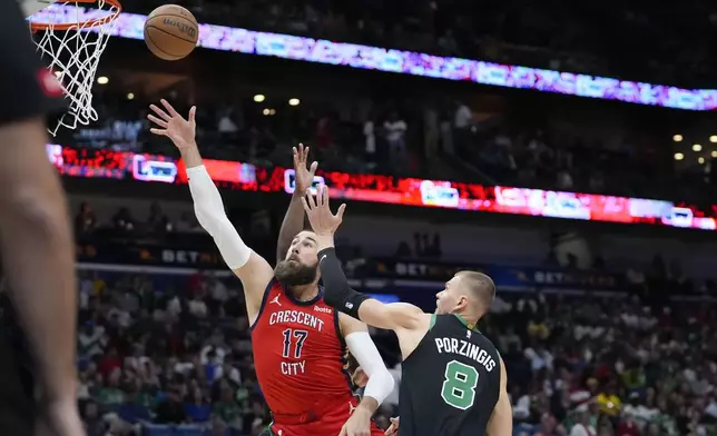 New Orleans Pelicans center Jonas Valanciunas (17) goes to the basket against Boston Celtics center Kristaps Porzingis (8) in the first half of an NBA basketball game in New Orleans, Saturday, March 30, 2024. (AP Photo/Gerald Herbert)