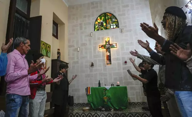 Same-sex couples stand in prayer with outstretched hands inside the Metropolitan Community Church, an LGBTQ+ inclusive house of worship, in Matanzas, Cuba, Friday, Feb. 2, 2024. Cuba repressed gay people after its 1959 revolution led by Fidel Castro and sent many to labor camps. (AP Photo/Ramon Espinosa)