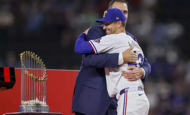 Texas Rangers pitcher Jacob deGrom, front, hugs general manager Chris Young, back, during the World Series ring ceremony before a baseball game against the Chicago Cubs, Saturday, March 30, 2024, in Arlington, Texas. (AP Photo/Gareth Patterson)