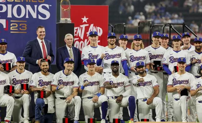 Texas Rangers players, coaches and the owner pose together after receiving their World Series rings before a baseball game against the Chicago Cubs, Saturday, March 30, 2024, in Arlington, Texas. (AP Photo/Gareth Patterson)