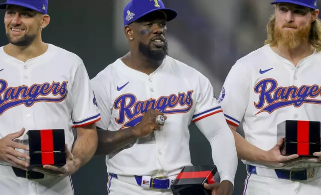 Texas Rangers players Nathan Eovaldi, left; Adolis Garcia, center; and Jon Gray, right, pose with their World Series rings before a baseball game against the Chicago Cubs, Saturday, March 30, 2024, in Arlington, Texas. (AP Photo/Gareth Patterson)