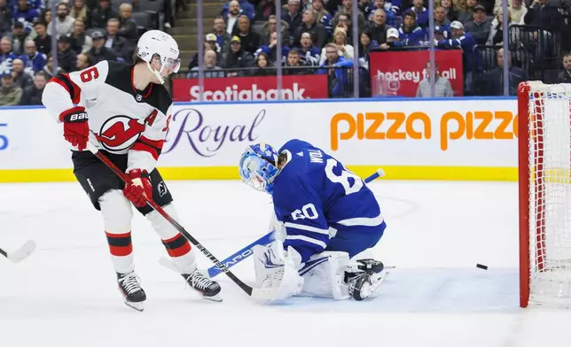 New Jersey Devils center Jack Hughes (86) scores on Toronto Maple Leafs goaltender Joseph Woll (60) during the third period of an NHL hockey game in Toronto on Tuesday, March 26, 2024. (Cole Burston/The Canadian Press via AP)