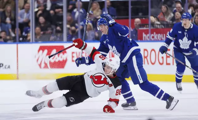 New Jersey Devils center Jack Hughes (86) and Toronto Maple Leafs right wing Pontus Holmberg (29) collide during the second period of an NHL hockey game Tuesday, March 26, 2024, in Toronto. (Cole Burston/The Canadian Press via AP)