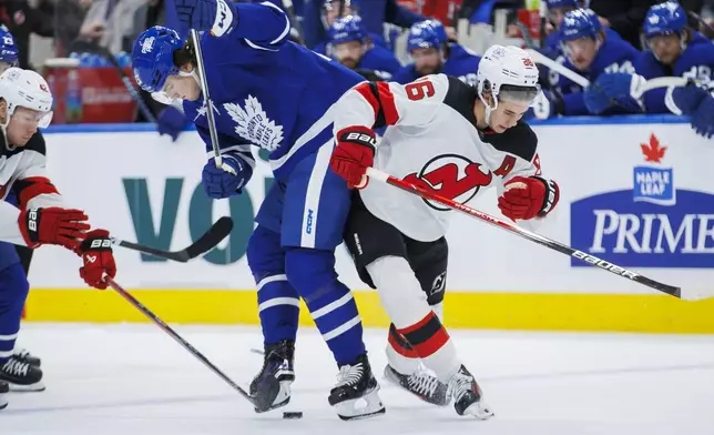 Toronto Maple Leafs left wing Matthew Knies (23) and New Jersey Devils centre Jack Hughes (86) compete for the puck during the second period of an NHL hockey game Tuesday, March 26, 2024, in Toronto. (Cole Burston/The Canadian Press via AP)