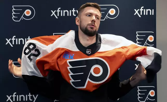 Philadelphia Flyers' Ivan Fedotov puts on his new Flyers jersey during an NHL hockey press conference, Friday, March 29, 2024, in Voorhees, N.J. (AP Photo/Chris Szagola)