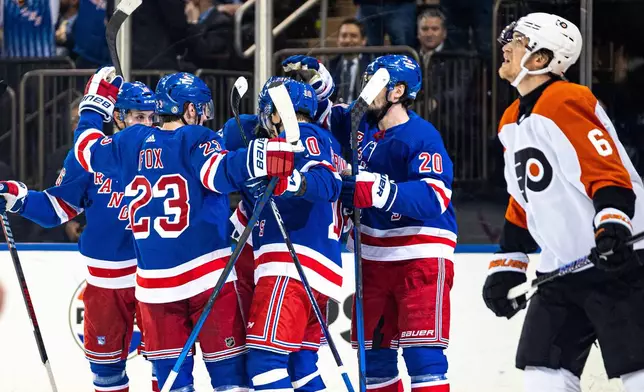 New York Rangers celebrate a goal by Mika Zibanejad, obscured at center, as Philadelphia Flyers' Travis Sanheim (6) looks at the scoreboard during the second period of an NHL hockey game Tuesday, March 26, 2024 in New York. (AP Photo/Peter K. Afriyie)