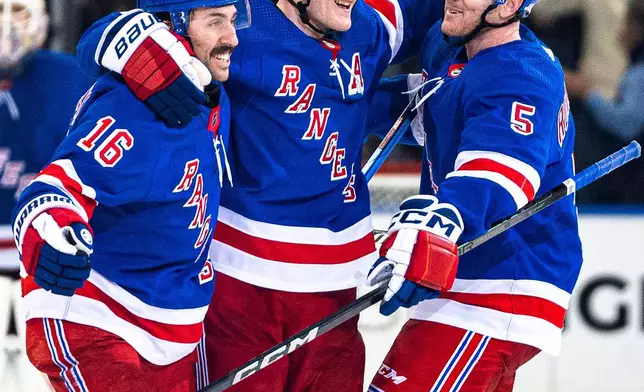 New York Rangers' Vincent Trocheck (16) and Chad Ruhwedel (5) celebrate with Adam Fox after Fox scored against the Philadelphia Flyers in overtime of an NHL hockey game Tuesday, March 26, 2024 in New York. (AP Photo/Peter K. Afriyie)