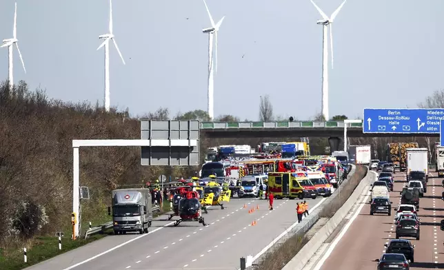Emergency vehicles and rescue helicopters are seen at the scene of the accident on the A9, near Schkeuditz, Germany, Wednesday March 27, 2024. (Jan Woitas/dpa via AP)