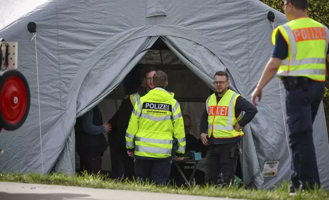 Police officers stand by a tent at the scene of the accident on the A9, near Schkeuditz, Germany, Wednesday March 27. 2024. (Jan Woitas/dpa via AP)