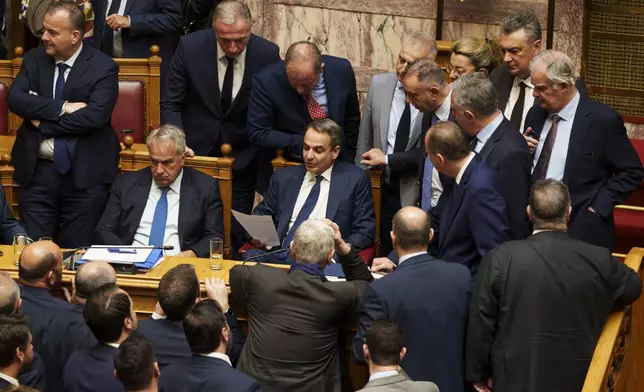 Greece Prime Minister Kyriakos Mitsotakis, center, reads a paper among his parties' lawmakers during a parliament session in Athens, Greece, Thursday, March 28, 2024. Greece's center-right government survived a motion of no-confidence late Thursday brought by opposition parties over its handling of the country's deadliest rail disaster. Parliament voted 159-141 against the motion following an acrimonious three-day debate. (AP Photo/Petros Giannakouris)