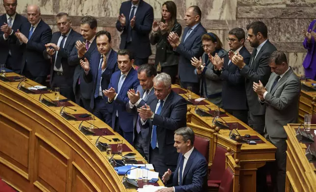 Greece Prime Minister Kyriakos Mitsotakis, front center, is applauded by members of the Greek government during a parliament session in Athens, Greece, Thursday, March 28, 2024. Greece's center-right government survived a motion of no-confidence late Thursday brought by opposition parties over its handling of the country's deadliest rail disaster. Parliament voted 159-141 against the motion following an acrimonious three-day debate. (AP Photo/Petros Giannakouris)