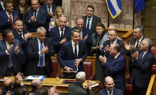 Greece Prime Minister Kyriakos Mitsotakis, center, is applauded by his partys' lawmakers during a parliament session in Athens, Greece, Thursday, March 28, 2024. Greece's center-right government survived a motion of no-confidence late Thursday brought by opposition parties over its handling of the country's deadliest rail disaster. Parliament voted 159-141 against the motion following an acrimonious three-day debate. (AP Photo/Petros Giannakouris)