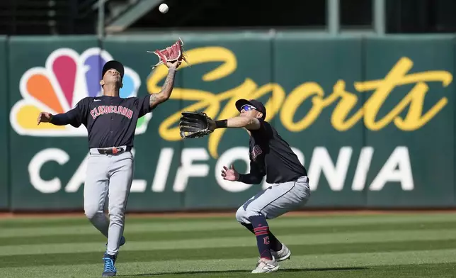 Cleveland Guardians shortstop Brayan Rocchio, left, catches a fly out hit by Oakland Athletics' Ryan Noda next to center fielder Tyler Freeman during the ninth inning of a baseball game in Oakland, Calif., Saturday, March 30, 2024. (AP Photo/Jeff Chiu)