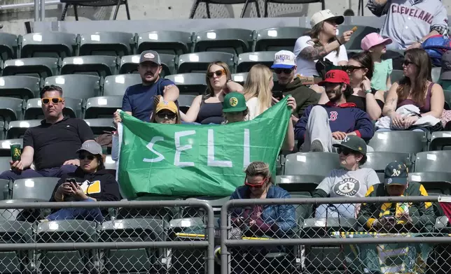 Fans hold up a sign calling for Oakland Athletics management to sell the team during the fifth inning of a baseball game between the Athletics and the Cleveland Guardians in Oakland, Calif., Saturday, March 30, 2024. (AP Photo/Jeff Chiu)