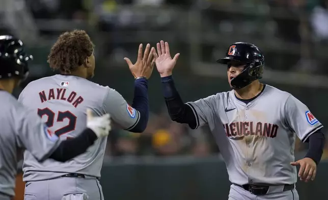 Cleveland Guardians' Andres Giménez, right, celebrates with Josh Naylor after scoring against the Oakland Athletics on Brayan Rocchio's two-run double during the fourth inning of a baseball game Thursday, March 28, 2024, in Oakland, Calif. (AP Photo/Godofredo A. Vásquez)