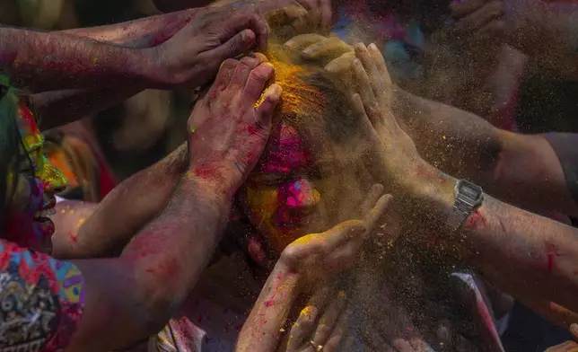 A girl has her face smeared with coloured powder as they celebrate Holi, the festival of colors in Mumbai, India, Monday, March 25, 2024. (AP Photo/Rafiq Maqbool)