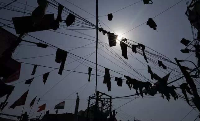 Clothes thrown by revelers hang from overhanging cables as they dance during celebrations to mark Holi, the Hindu festival of colors at loknath Prayagraj, northern Uttar Pradesh state, India, Monday March 25, 2024. (AP Photo/Rajesh Kumar Singh)
