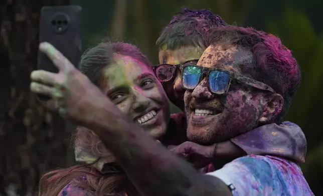 A family takes selfie as they celebrate Holi, the Hindu festival of colors, in Mumbai, India, Monday, March 25, 2024. (AP Photo/Rafiq Maqbool)