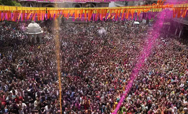 Devotees cheer as colored powder and water is sprayed on them during celebrations marking Holi at the Kalupur Swaminarayan temple in Ahmedabad, India, Sunday, March 24, 2024. (AP Photo/Ajit Solanki)