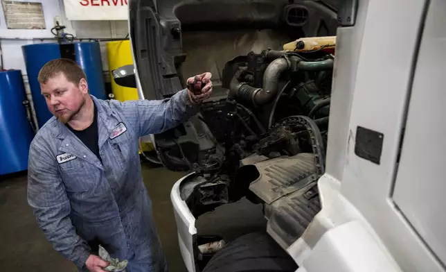 Big Truck Service owner Brandon Bauer, who says he has seen business drop by a third since the indefinite closure of the nearby Fishing Wars Memorial Bridge, does an oil change on a truck Tuesday, March 26, 2024, in Fife, Wash. The bridge has been closed since October 2023 after the Federal Highway Administration raised safety concerns, causing nearby business owners to notice a decrease in customers as drivers bypass their street. (AP Photo/Lindsey Wasson)