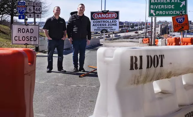 Marco Pacheco, left, owner of Jordan's Liquors and John Oliver, owner of The Local sports bar, pose at the closed onramp leading to the Washington Bridge, near their businesses, Friday, March 8, 2024, in East Providence, R.I. The closure of a section of the bridge, and onramps, due to failure of some bridge components, has caused a significant loss to local businesses. (AP Photo/Charles Krupa)