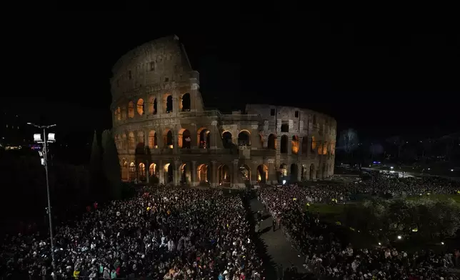 People stand in front of the Colosseum during a Via Crucis (Way of the Cross) torchlight procession on Good Friday, in Rome, Friday, March 29, 2024. (AP Photo/Andrew Medichini)