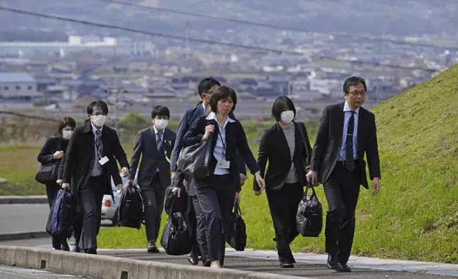 Japan's health ministry officials walk towards a plant operated by a subsidiary of Kobayashi Pharmaceutical Co. to conduct an on-site inspection in Kinokawa, south of Osaka, western Japan, Sunday, March 31, 2024. Japanese government health officials on Sunday inspected a factory producing health supplements linked to several deaths and the hospitalization of more than 100 others, one day after the authorities investigated another plant that manufactured the product. (Yohei Fukai/Kyodo News via AP)