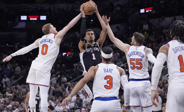 San Antonio Spurs center Victor Wembanyama (1) is defended by New York Knicks guard Donte DiVincenzo (0) and center Isaiah Hartenstein (55) during the second half of an NBA basketball game in San Antonio, Friday, March 29, 2024. (AP Photo/Eric Gay)