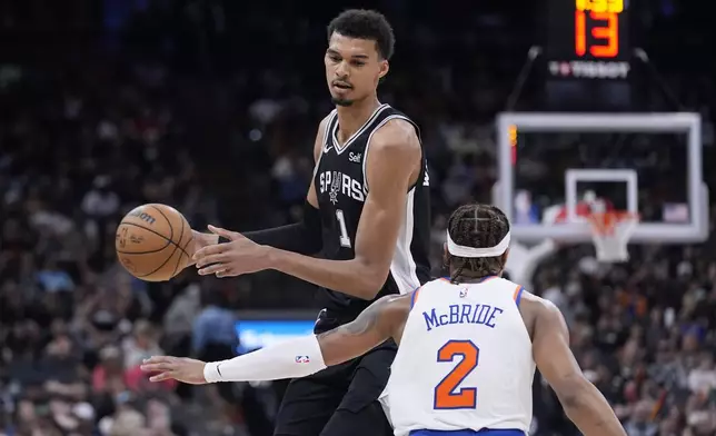 San Antonio Spurs center Victor Wembanyama (1) tries to move to ball past New York Knicks guard Miles McBride (2) during the second half of an NBA basketball game in San Antonio, Friday, March 29, 2024. (AP Photo/Eric Gay)